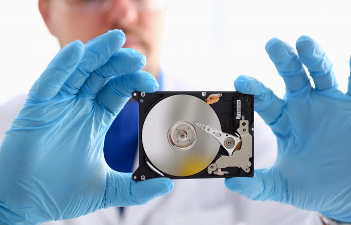 A male repairman wearing blue gloves A male repairman wearing blue gloves is holding a hard drive from computer or laptop in hands. Performs fault diagnostics and performs urgent repairs recovery of lost data during deletion HDD closeup